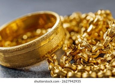 Close-up of a textured gold ring and thick gold chain link jewelry.