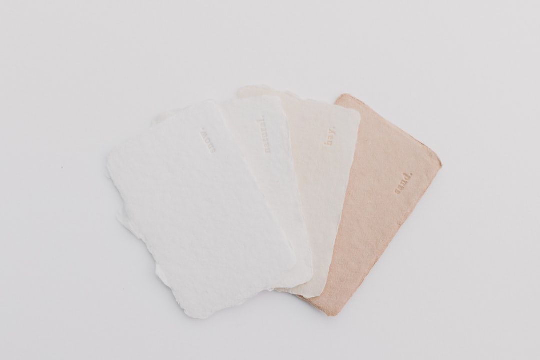Four textured paper samples in neutral shades of white, cream, and tan.