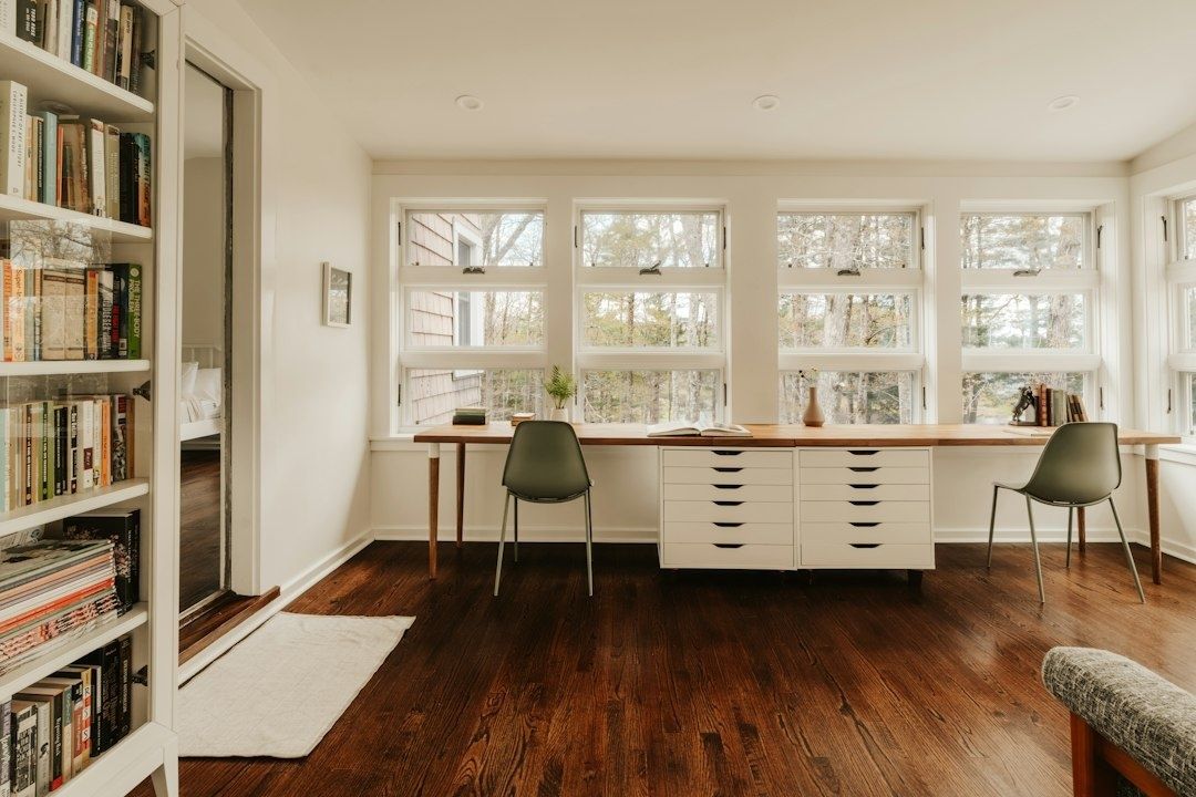 Bright home library with organized bookshelves, desk, and large windows
