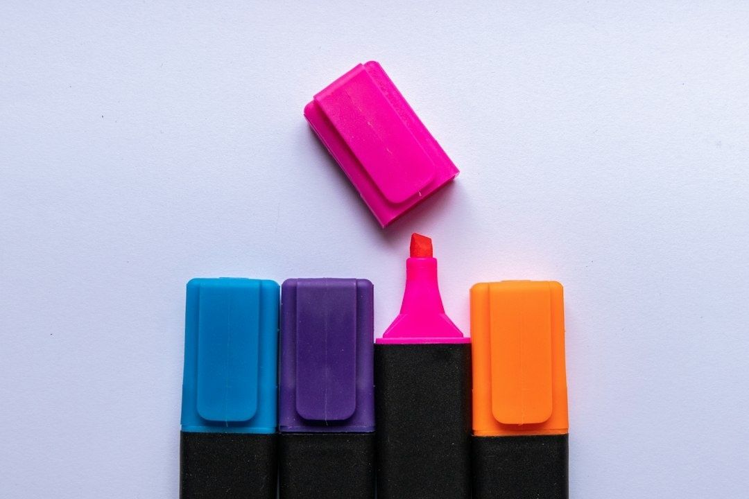 Bright highlighters arranged on a pale surface for reading notes