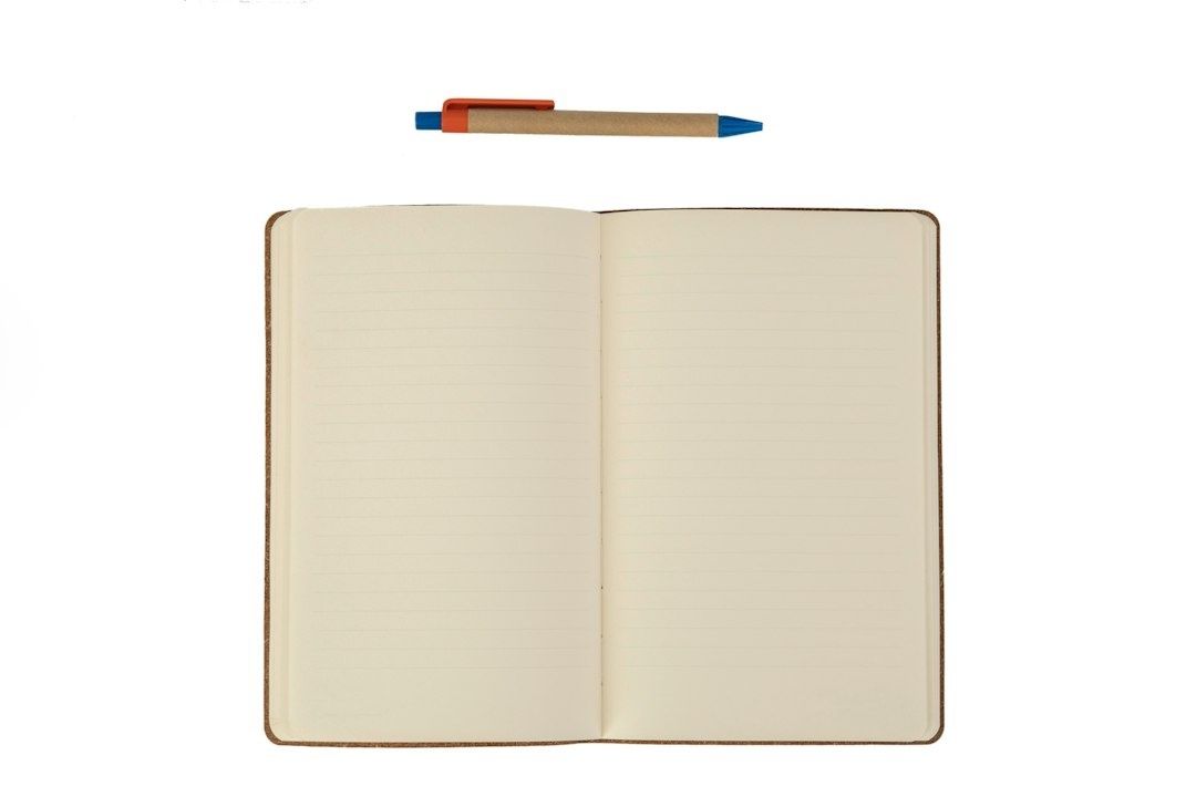 Open lined notebook with a blue-and-orange pen above it
